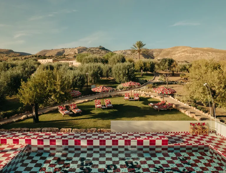 The red-and-white checkerboard pool at Braccialieri Resort surrounded by olive trees and lounge chairs