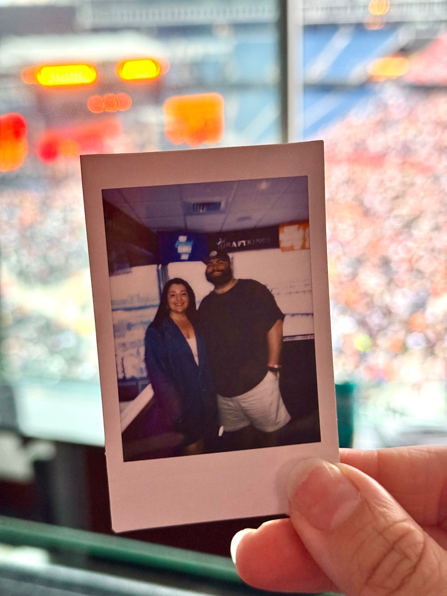 A polaroid of Jaime and Nolan held up in a stadium suite