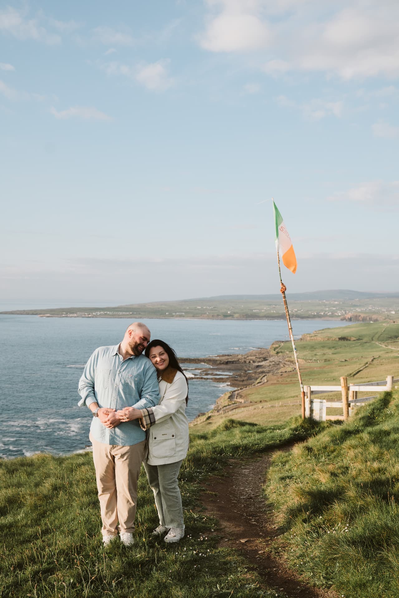 Jaime and Nolan on the coast path beside an Irish flag